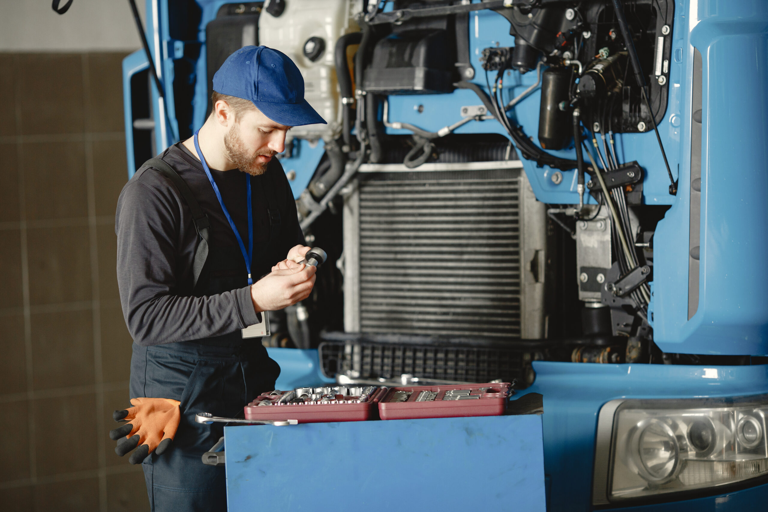 Two men repairing a blue truck with a tools