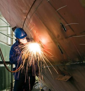Welding new steel plates on a ship's hull during repair work on a ship in a dry dock.